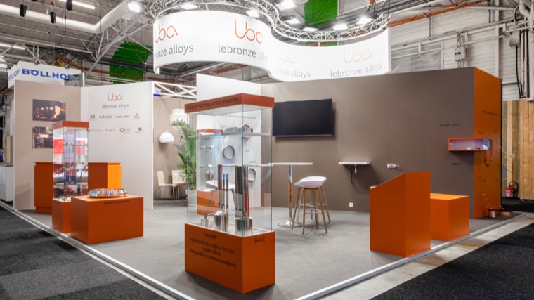 Stand gris et orange avec vitrines sur socles et suspension circulaire