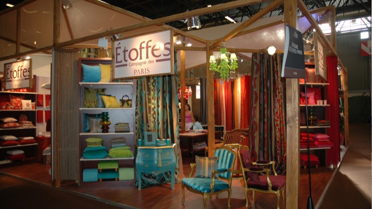 Stand à structure bois présentant rideaux, coussins et mobilier de style